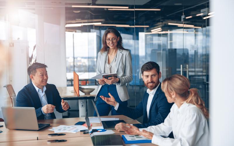 group of adults working around computers on table