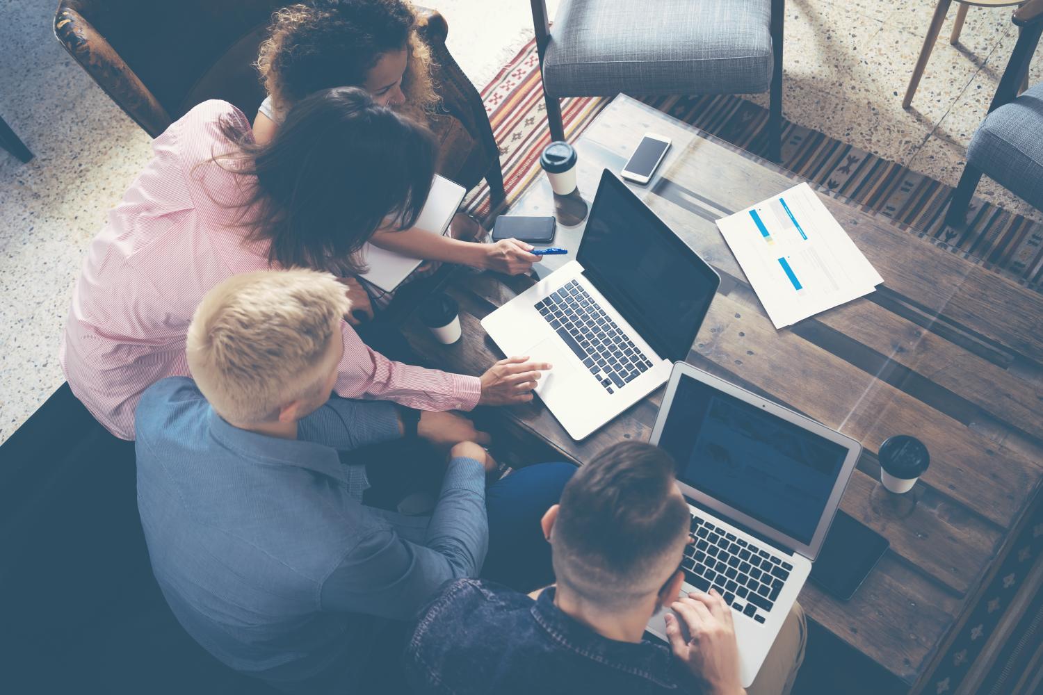 group of adults working around computers on table