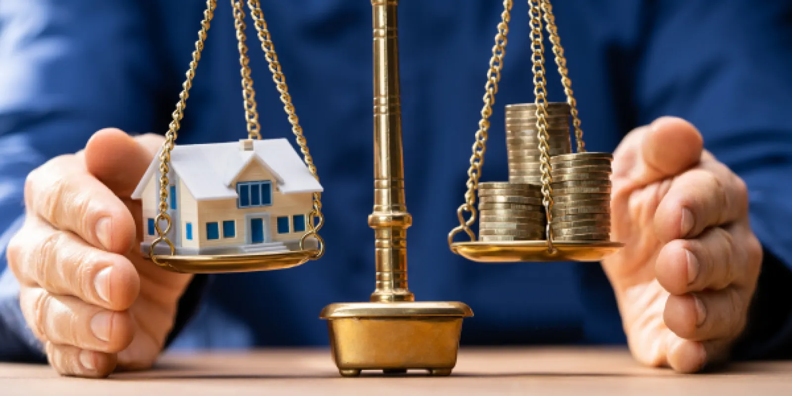 house and coins on a scale