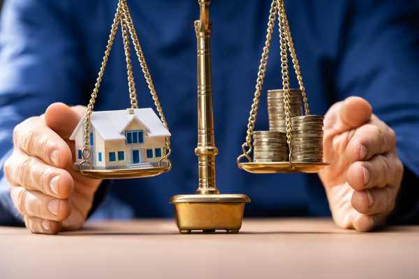 house and coins on a scale